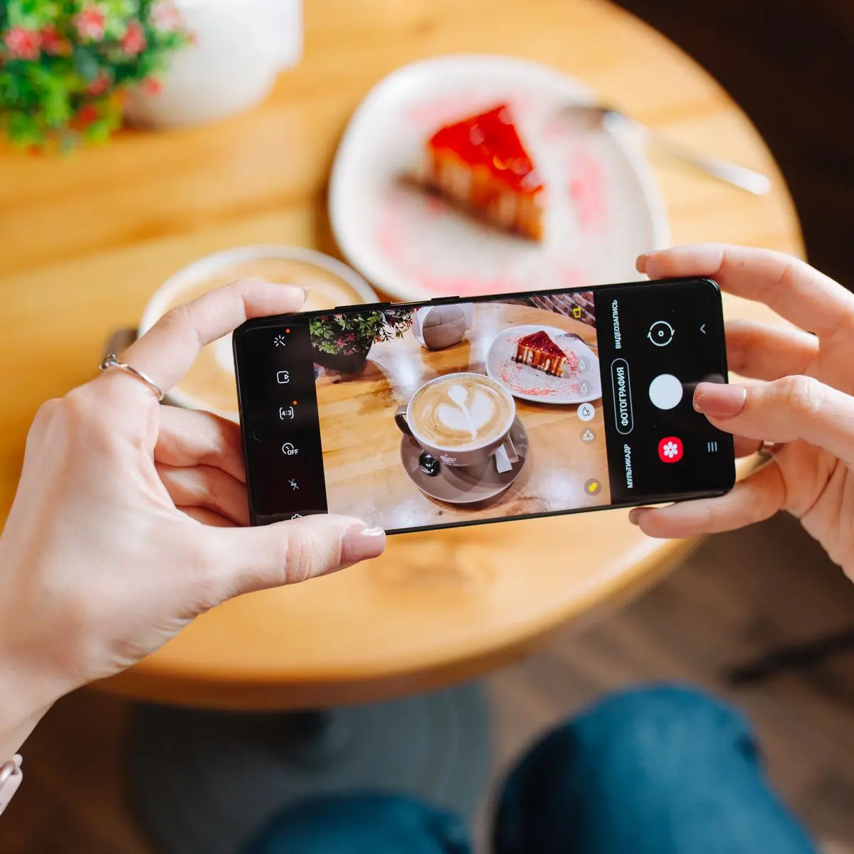 Femme photographiant un café et une part de gâteau avec son smartphone à table