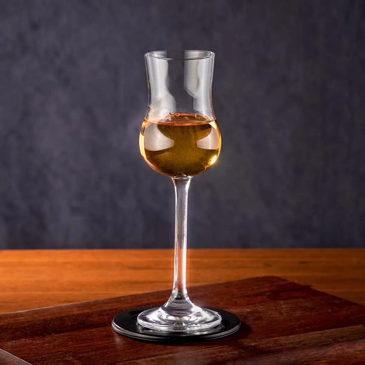 Verre Glencairn rempli d'un vin doré posé sur une table en bois pour une dégustation à l'aveugle